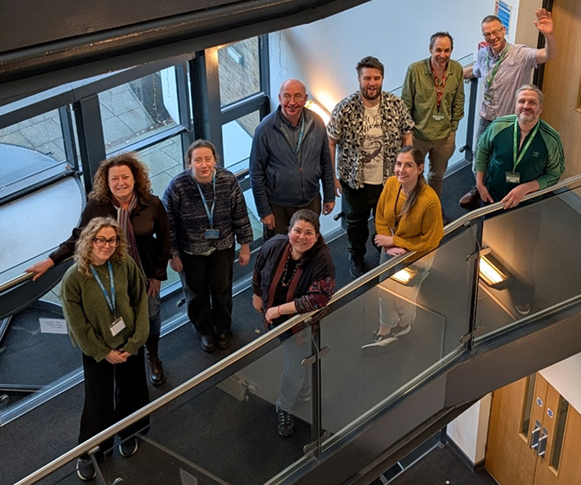 Looking down on 10 people standing on a second floor walkway